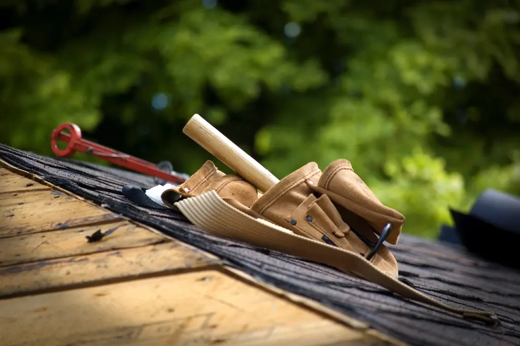 Ceinture porte-outils et marteau posés sur une toiture en bardeaux